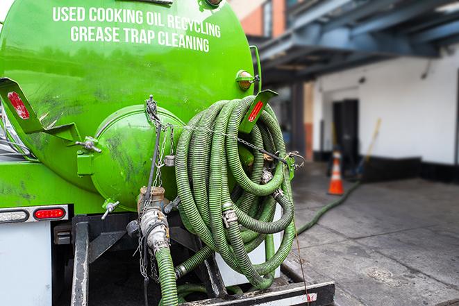 a professional plumber using a pump to empty a grease trap in Birmingham